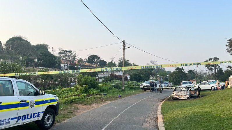 A yellow police tape with the words SA Police Service with several vehicles in the background