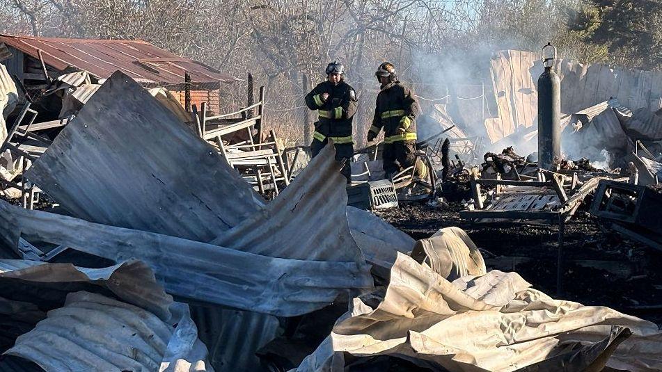 Firefighters inspect the scene following a fire at a nursing home which has killed 16 people in Pitrufquen, Chile on 12 September 2026.