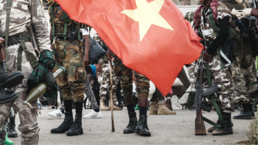 The feet and legs of TPLF soldiers seen behind a Tigray flag - with a red background and yellow star - archive shot.