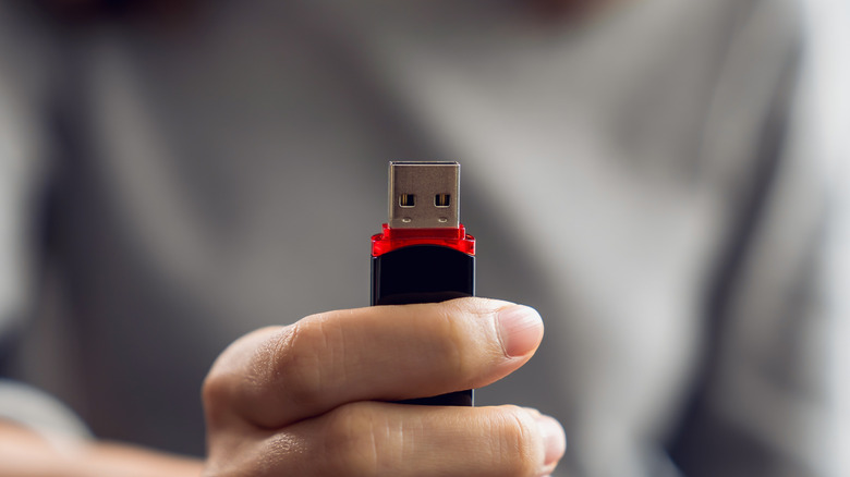 A hand holding a USB plug against a blurred background