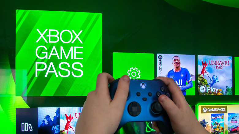 Close-up of hands holding an Xbox controller with software tiles in the background