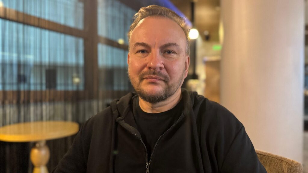 Serhii Beskrestnov speaking to the BBC in Kyiv. He is sitting in a chair wearing a black hoodie over a black t-shirt