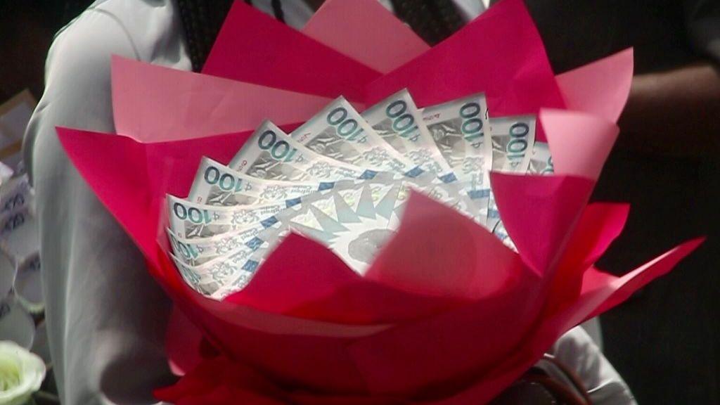 A bouquet made from folded Ghanaian cedi banknotes, wrapped in bright red paper