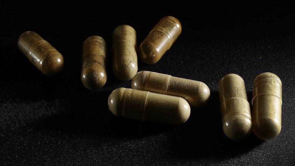 Kratom pills on a black back drop