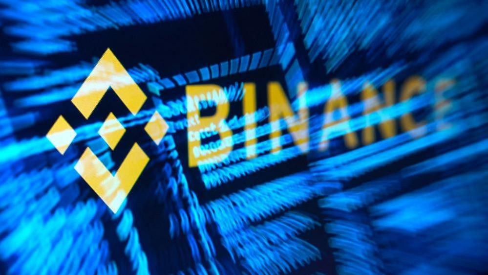 Binance logo in yellow over stylised and hacker code in blue