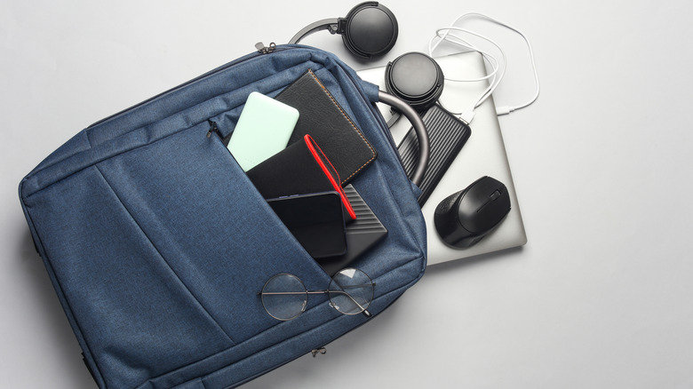 A backpack with a laptop, power bank, headphones, tablet, charging cables, and more.