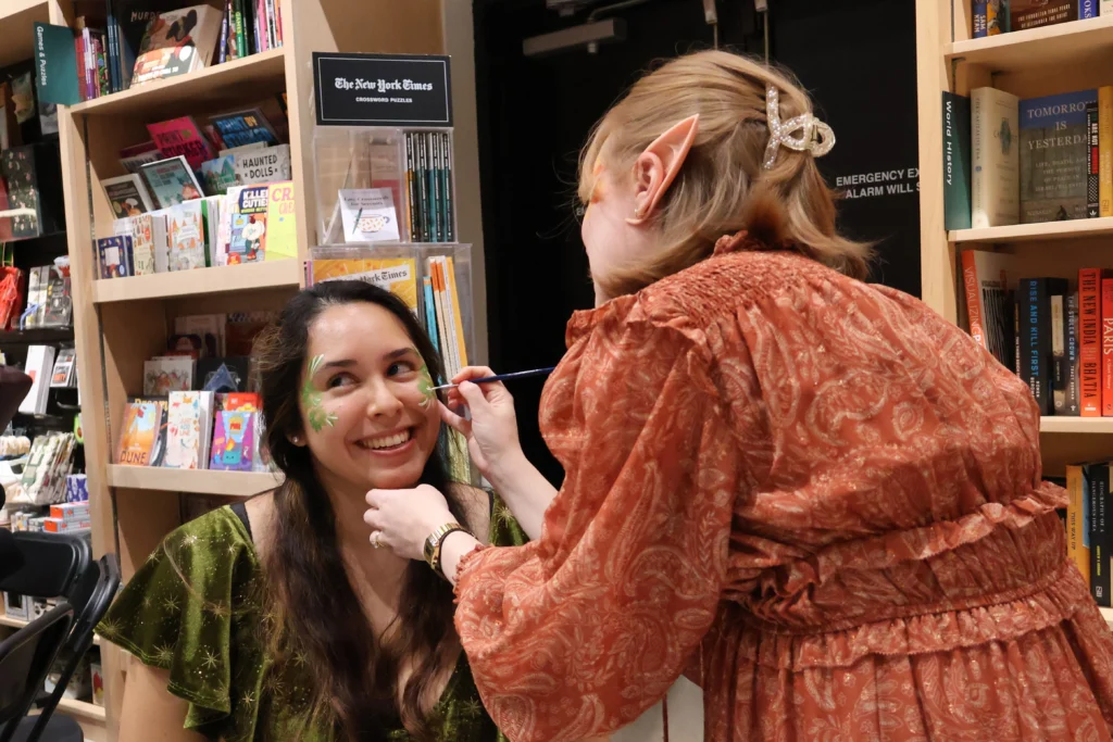 Dalia Luque, left, has her face painted by Amber Lovold, one of the organizers of a midnight release party at Politics and Prose in Washington, D.C. They are celebrating the publication of A Court of Splintered Harmony, the latest installment of Sarah J. Maas